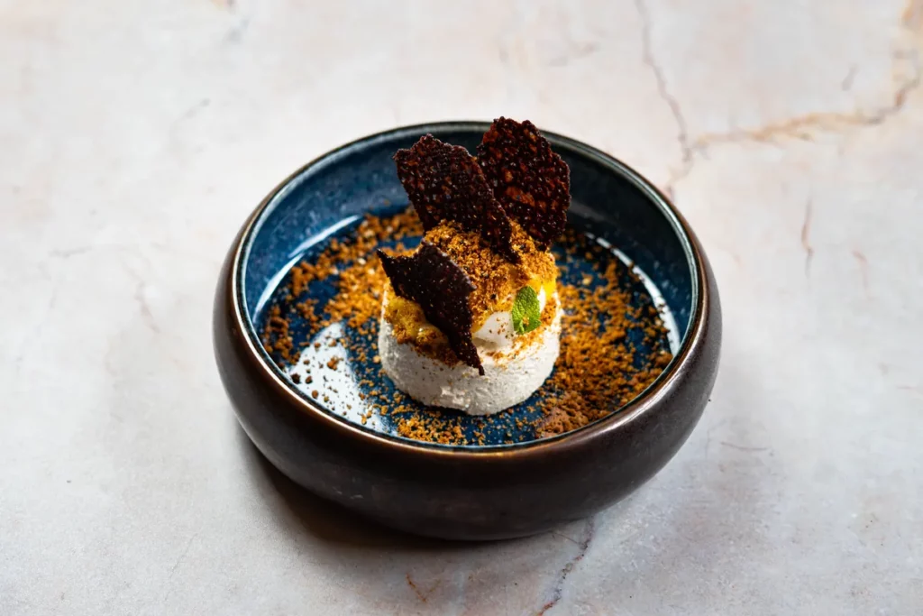 Mus chałwowy z palonym masłem i sezamem podany w ceramicznym półmisku.