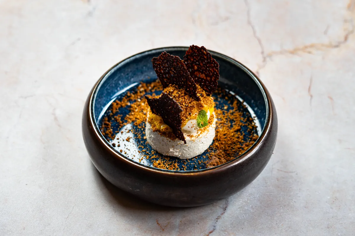 Mus chałwowy z palonym masłem i sezamem podany w ceramicznym półmisku.